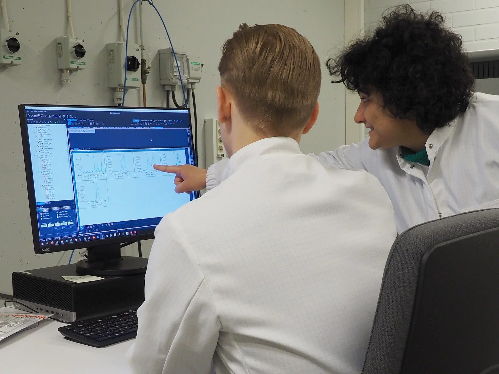 Two scientists analyzing semiconductor data on a computer screen in a research lab environment