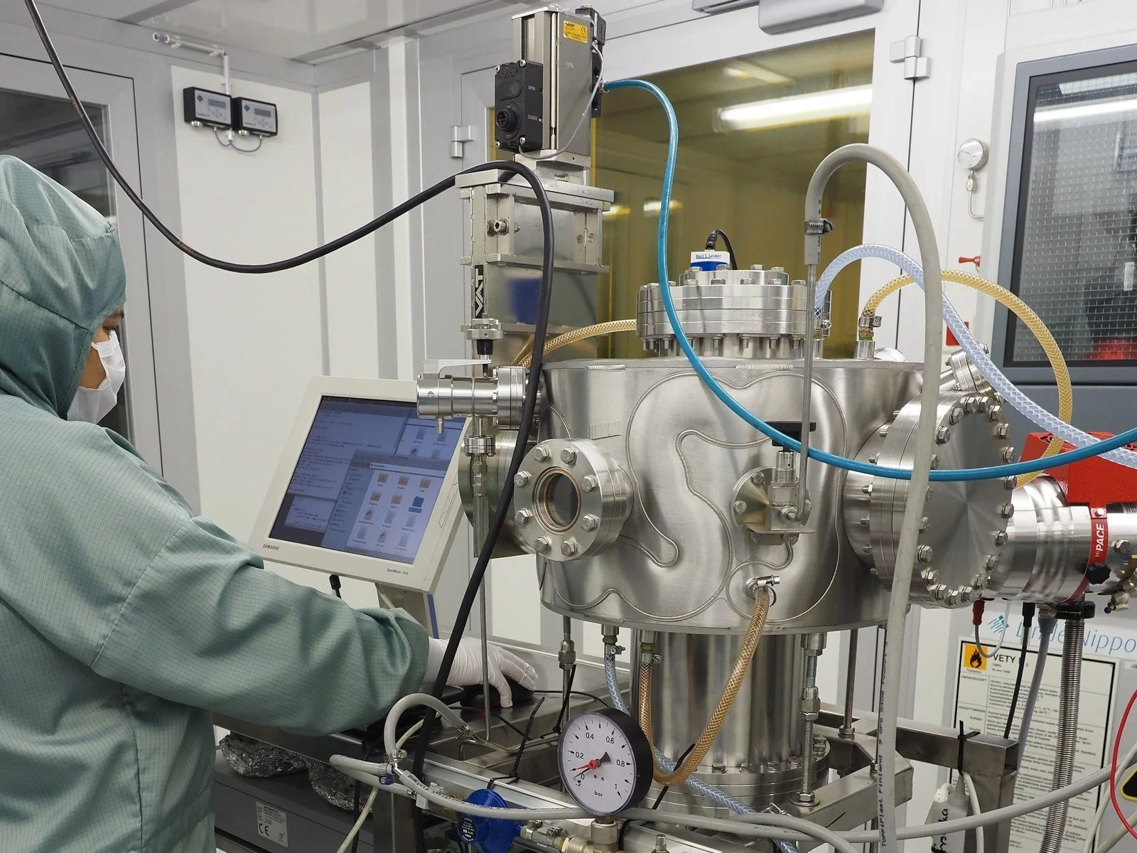 Scientist operating advanced semiconductor vacuum chamber system via touchscreen in a cleanroom environment