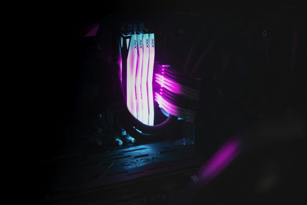 Close-up of RGB-illuminated XPG RAM modules installed in a custom-built PC with glowing power cables